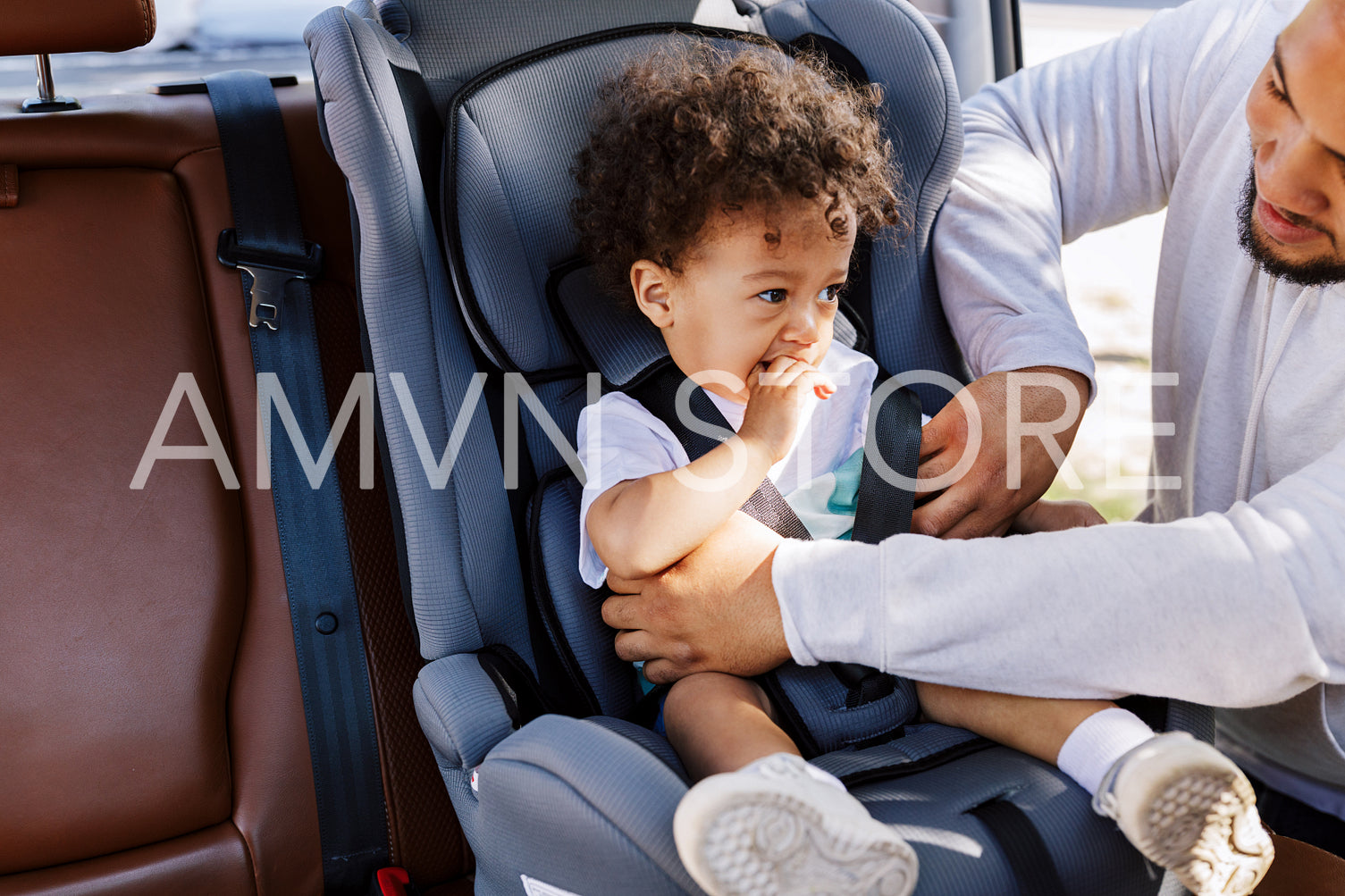 Young man fasten his son in a baby seat	