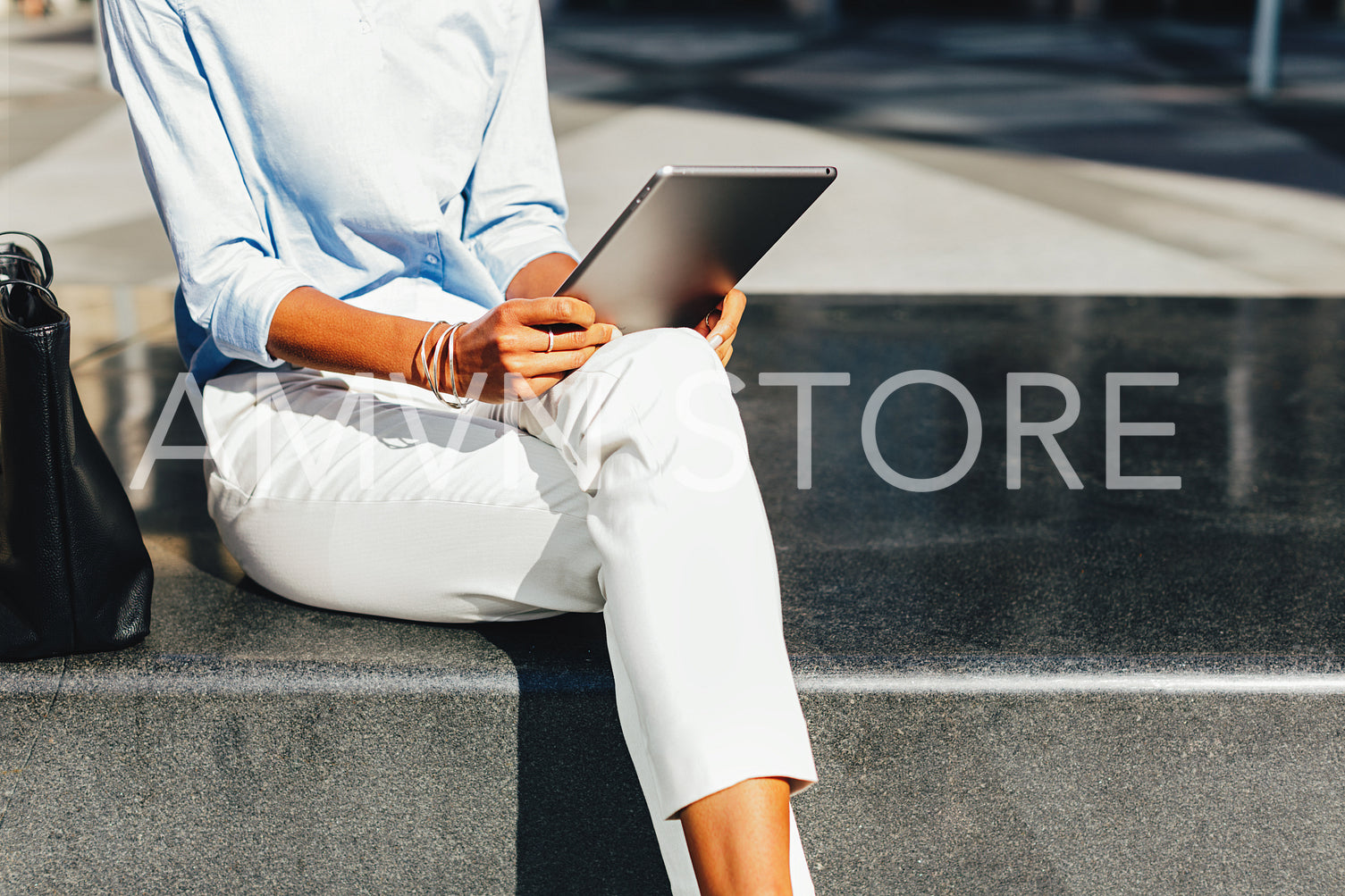 Unrecognizable businesswoman using a digital tablet while sitting outdoors	