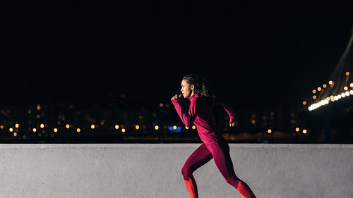 Young female jogger exercising in the evening. Woman running at embankment.