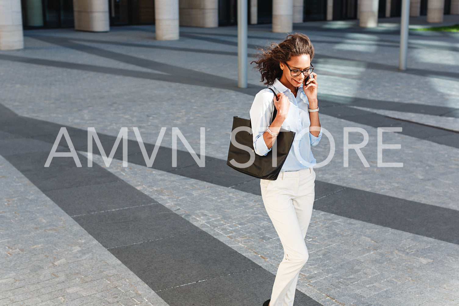 Modern businesswoman talking on mobile phone while walking on a street	