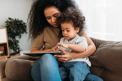 Mother and son sitting on the sofa and using digital tablet