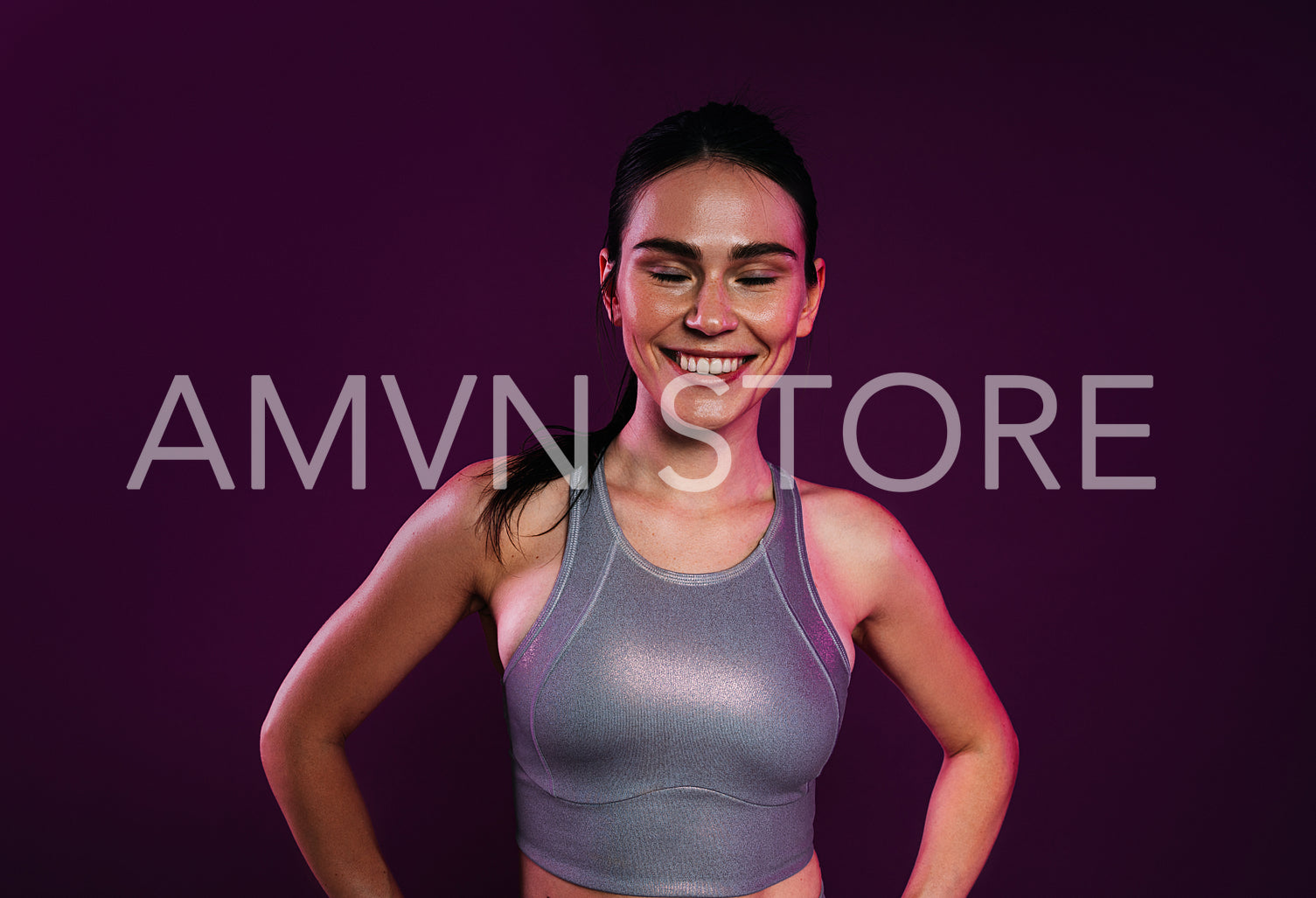 Portrait of a cheerful sportswoman
in silver fitness wear against a magenta backdrop