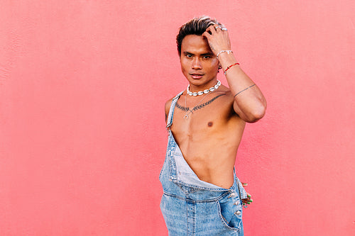 Young handsome guy adjusting his hair while looking at camera against pink wall