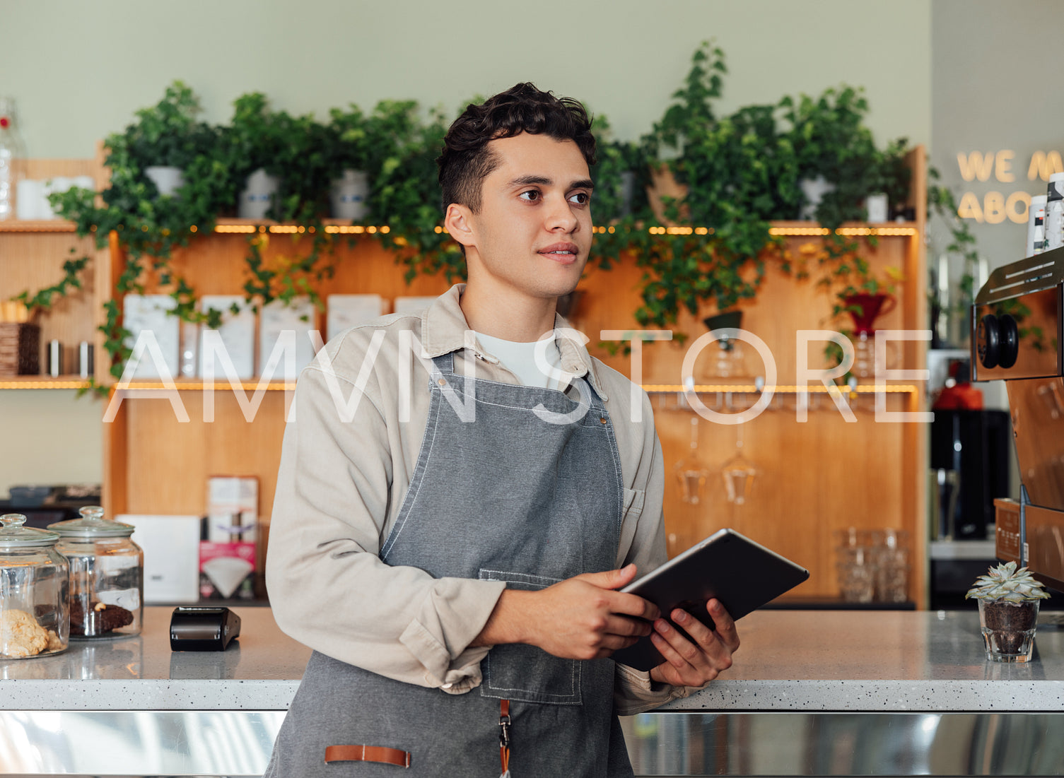 Male bartender holding a digital tablet at counter. Coffee shop owner with a portable computer.