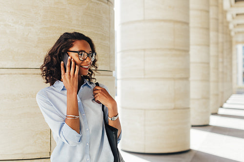 Businesswoman talking on smartphone while standing on city street at office building