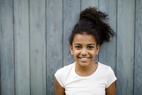 Horizontal shot of happy cute girl standing at wall outdoors