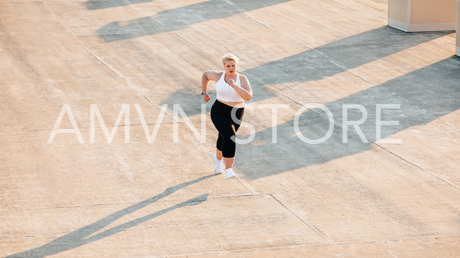 Plus size woman running on a roof. Young oversize female doing cardio training outdoors.	