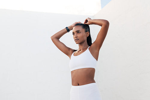 Confident sportswoman adjusting her hair while standing outdoors in a white location