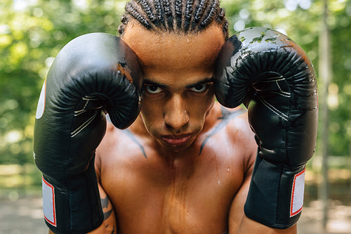 Close up portrait of a sweated kickboxer with gloves and mouth guard looking at the camera