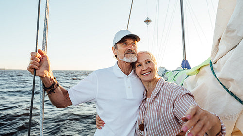 Portrait of a beautiful mature couple standing on a sailboat enjoying a vacation and looking away