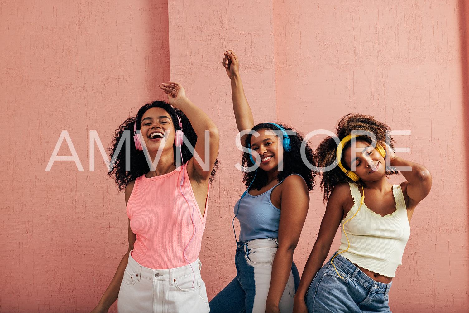 Three women having fun and dancing while listening to music with headphones