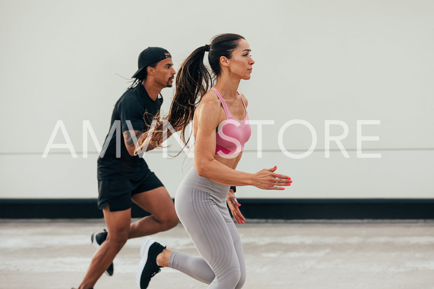 Two athletes running together outdoors. Woman and man sprinting on the rooftop.