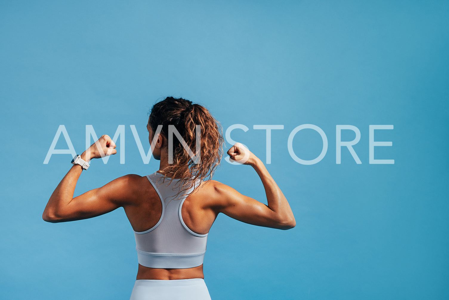 Rear view of young woman showing her biceps on blue background w