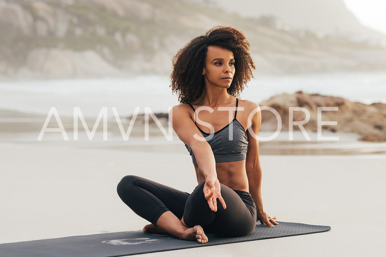 Woman doing yoga meditation. Young female with crossed legs at sunset looking away.