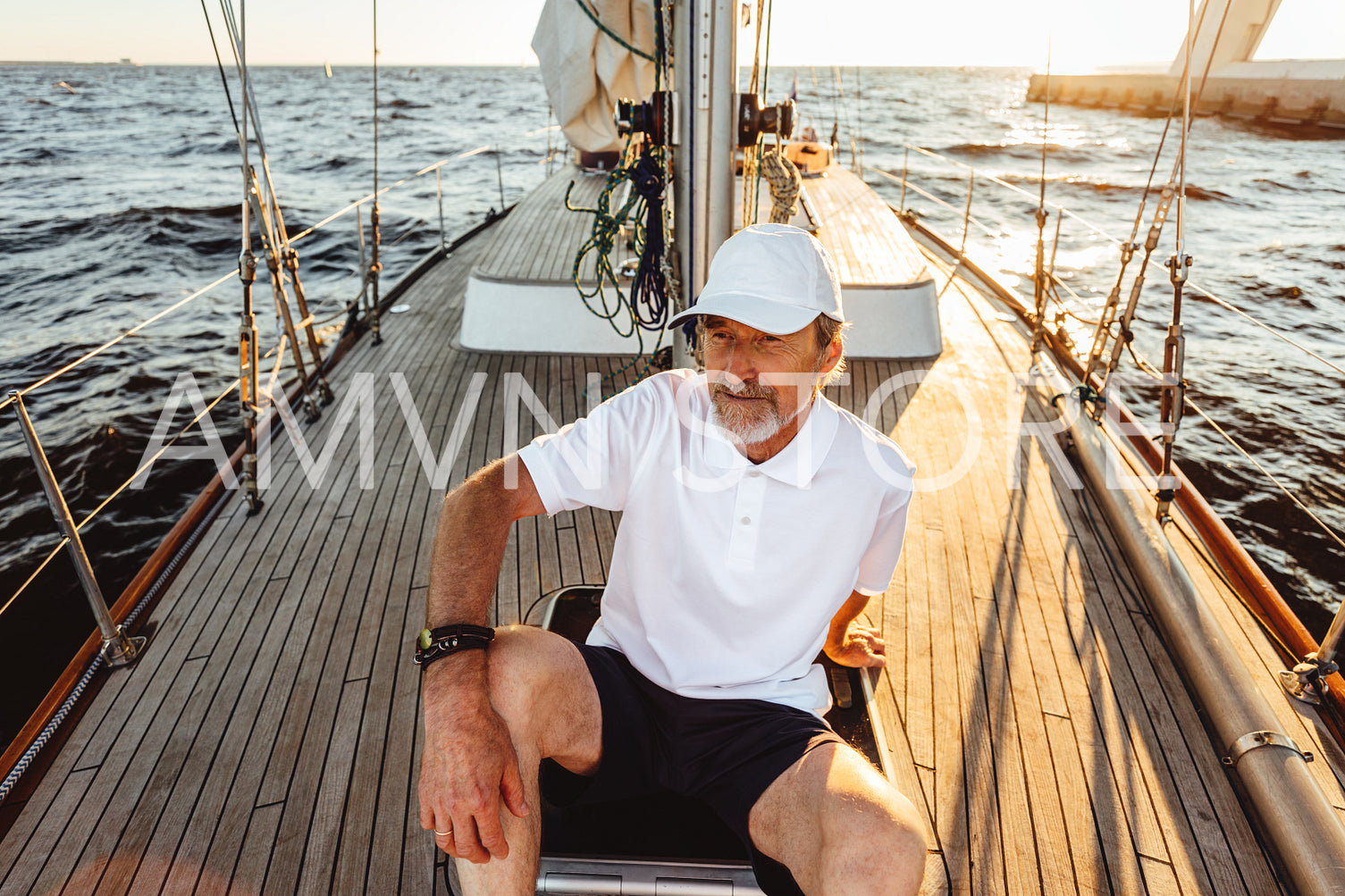 Senior man sitting on a deck of his yacht and enjoying sunset. Mature captain relaxing on sailboat.	