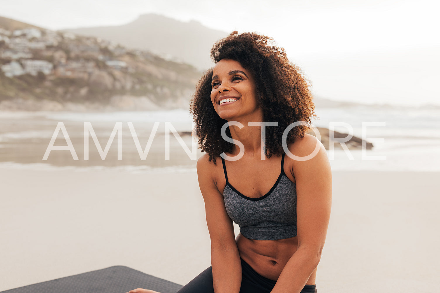 Cheerful woman relaxing after training while sitting on a beach