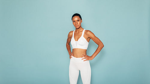 Portrait of a muscular fitness model on blue background looking at the camera