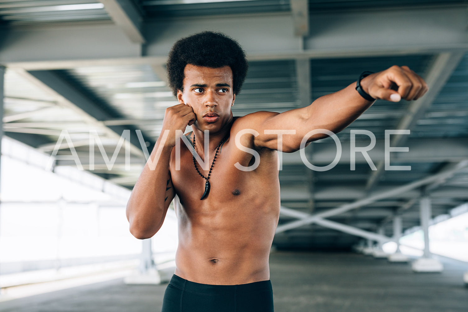 Male practicing boxing under a bridge, throwing a punch in front	