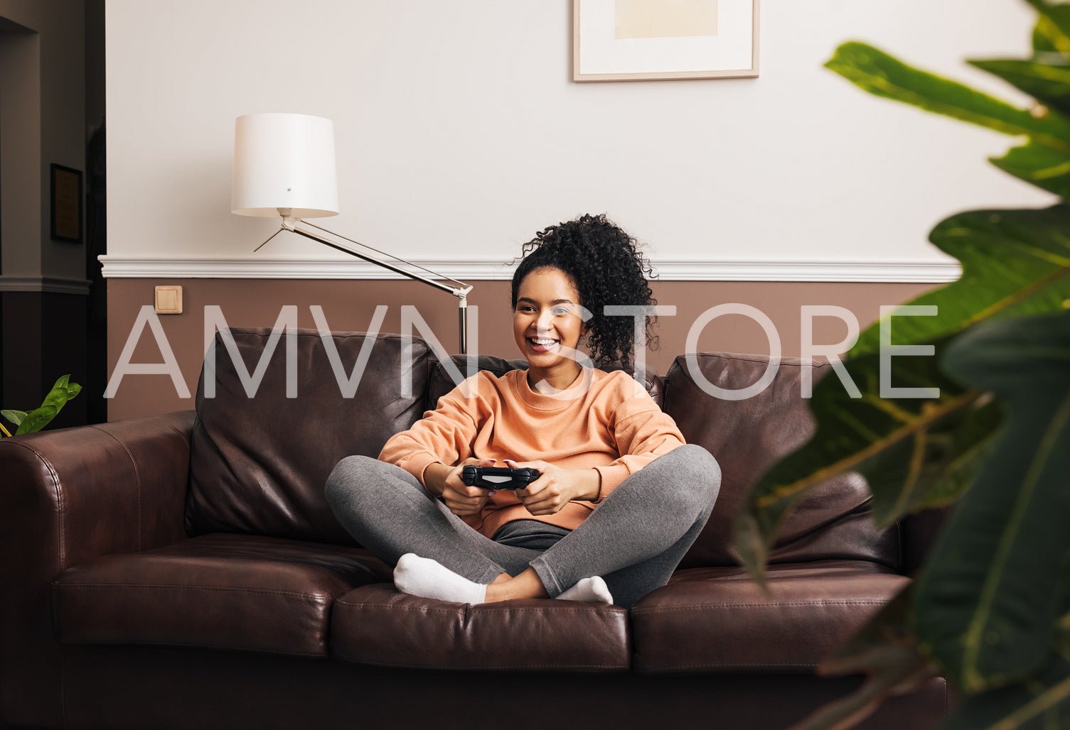 Cheerful female with joystick sitting on sofa playing video game while entertaining at home	