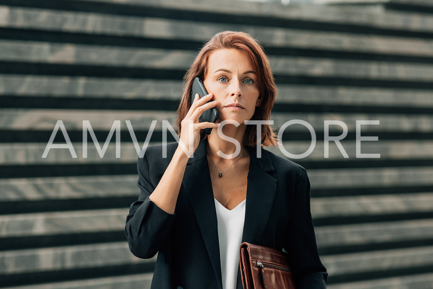 Businesswoman with ginger hair in formal wear making a phone call while standing outdoors