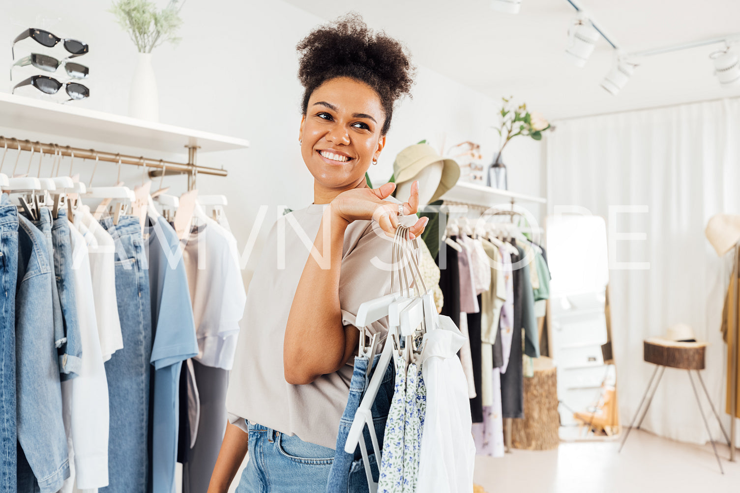 Young fashion store owner carrying clothes on hangers for arranging 