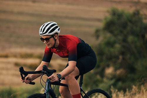 Female cyclist on her professional bicycle during training. Woman bicycle rider on road bike on country road.