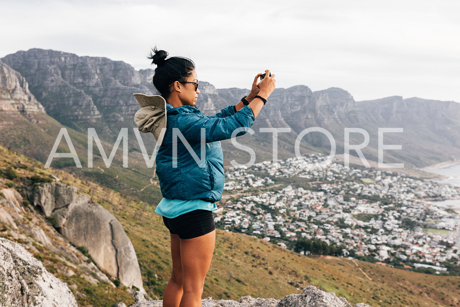 Side view of a woman in sports clothes taking photographs on mobile phone during hiking