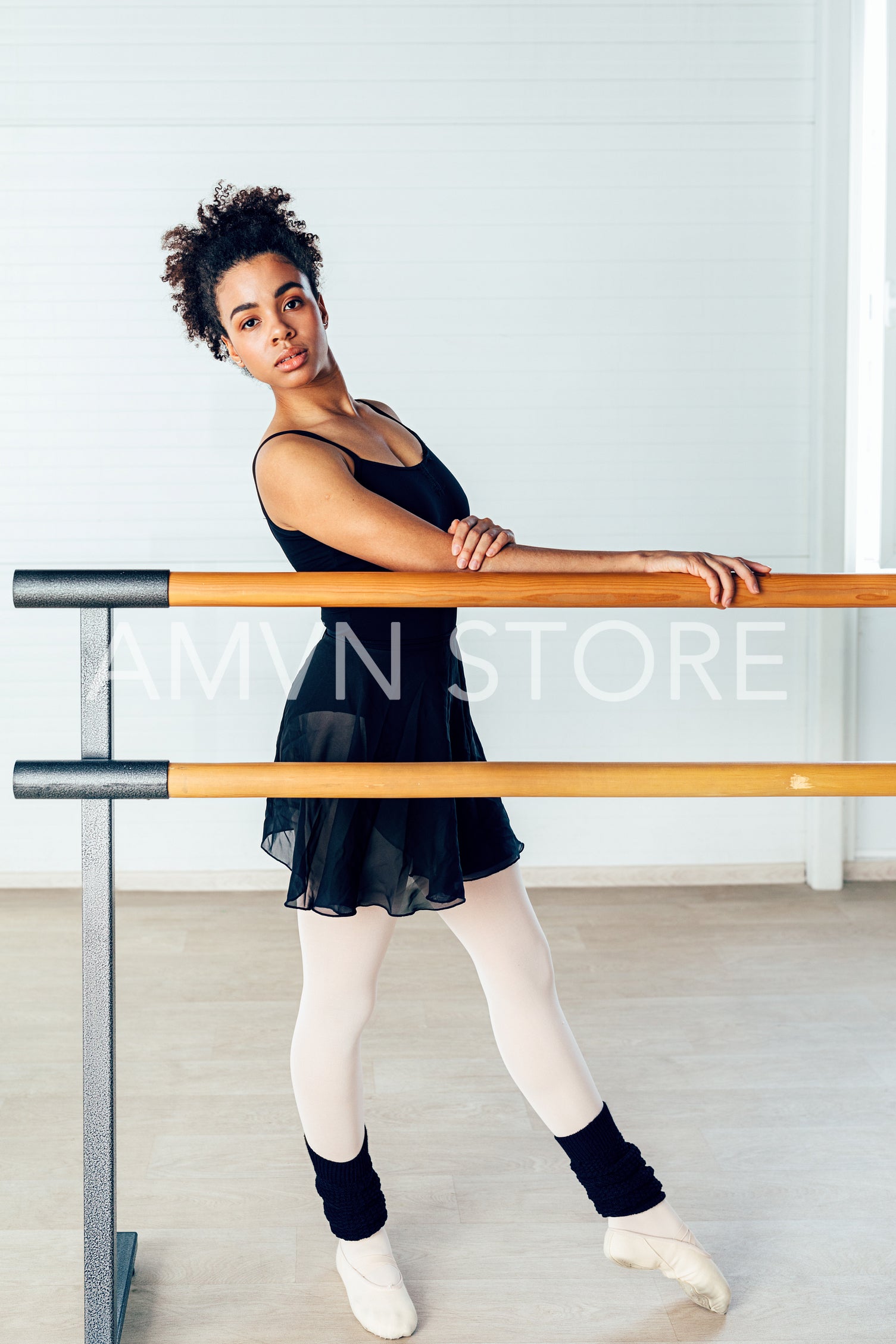 Young ballerina standing at barre in a small dancing studio	