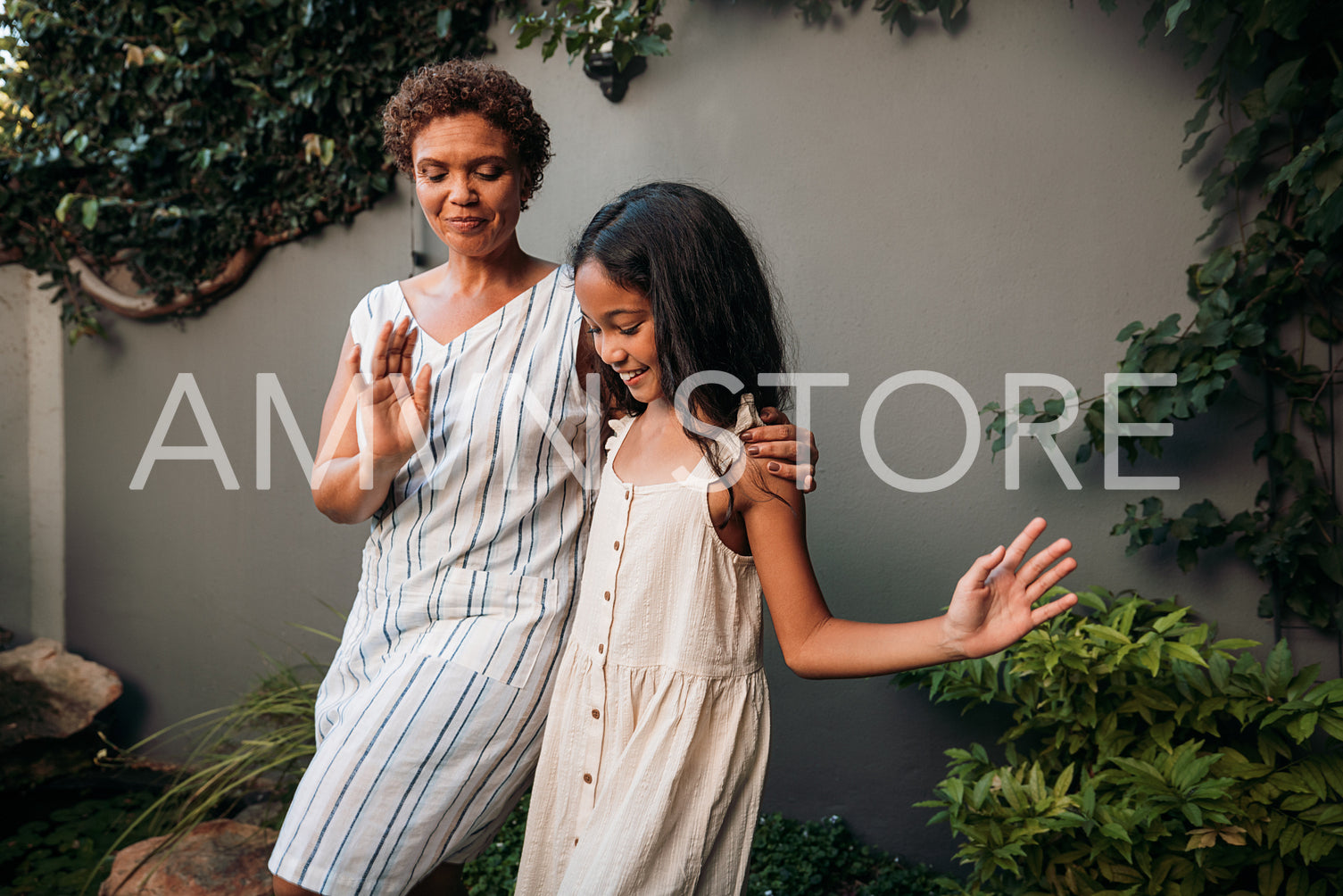 Granny and girl learning dance moves together on a backyard