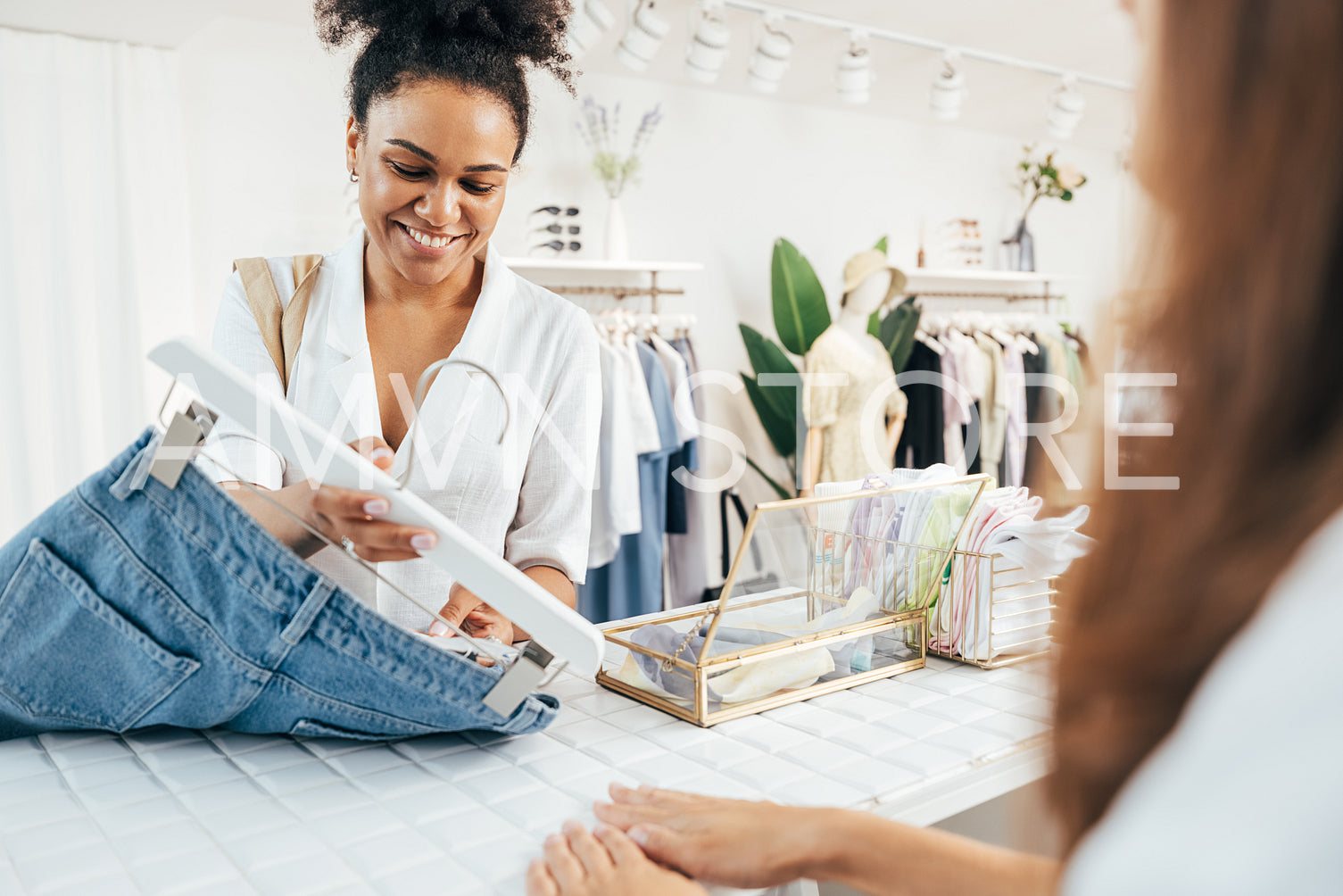 Female buyer standing at counter with jeans and looking at tag