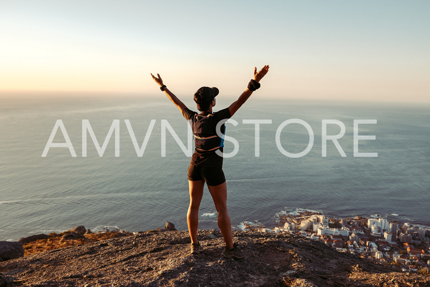 Rear view of fit woman standing on mountain top looking at view with arms wide open