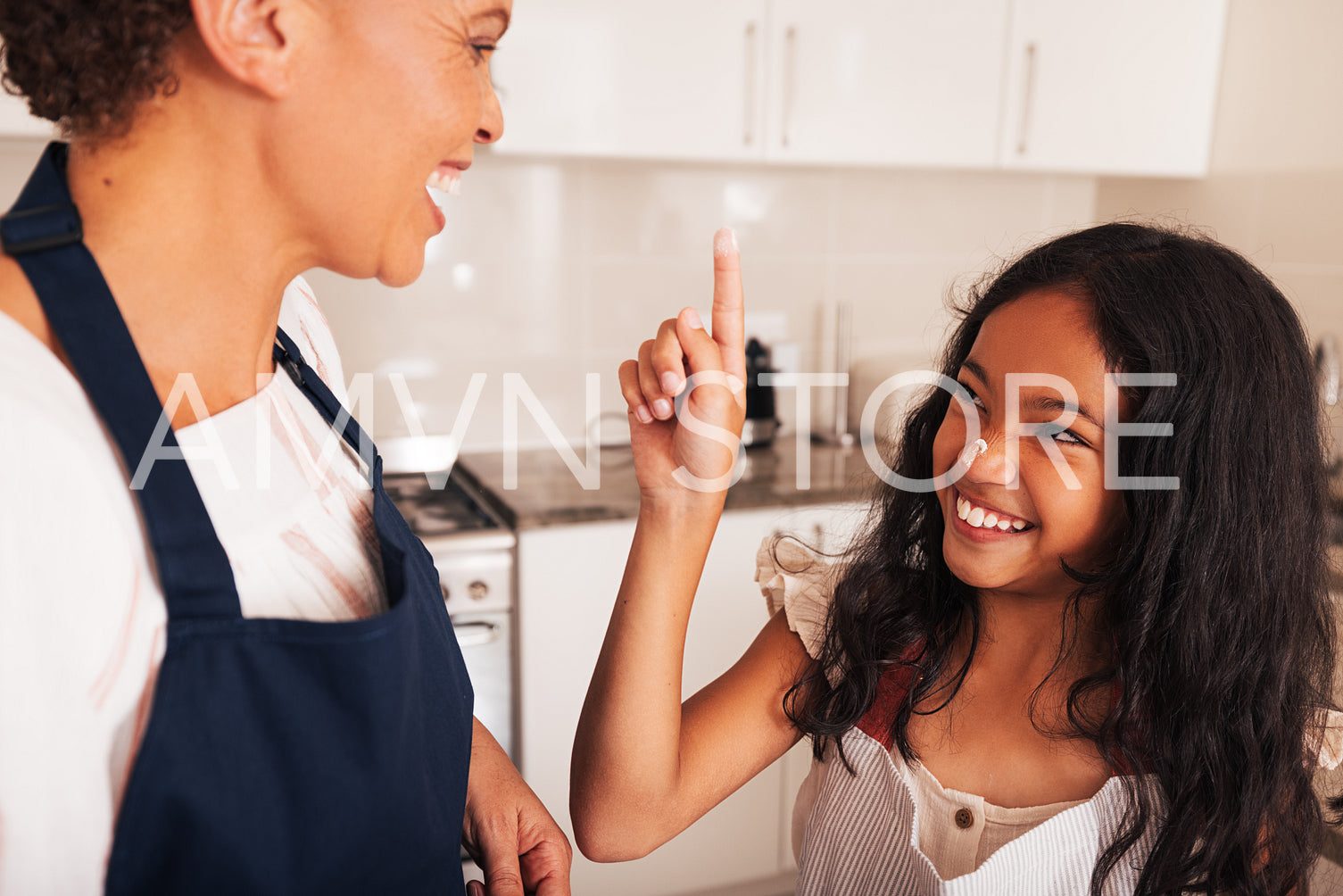 Smiling girl trying to make marks on granny's face using flour