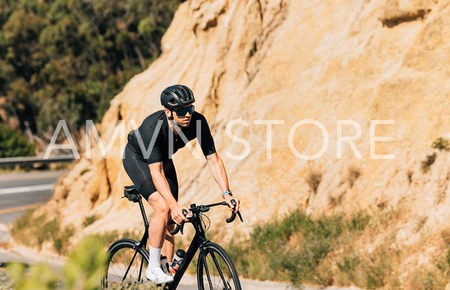 Fit cyclist on his road bike. Young male in a helmet and eyeglasses is on the road at the mountain.