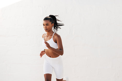 Slim woman in white fitness others running outdoors. Young slim fitness influencer jogging outdoors.