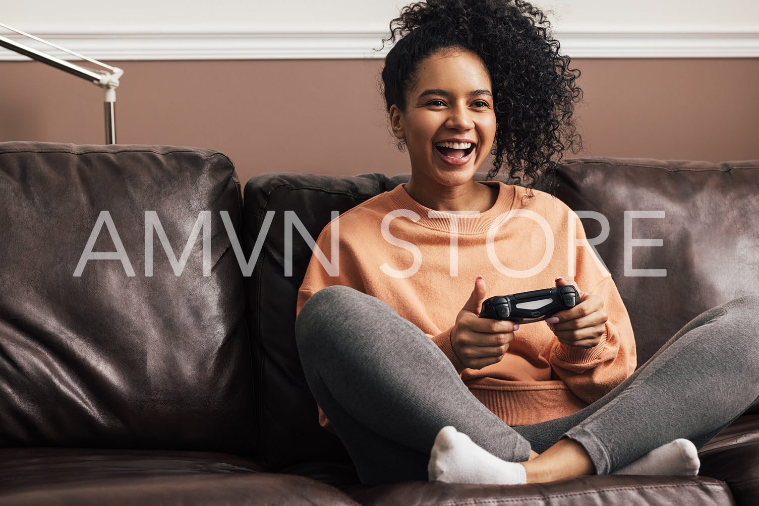 Happy young woman holding a game controller sitting on sofa at home