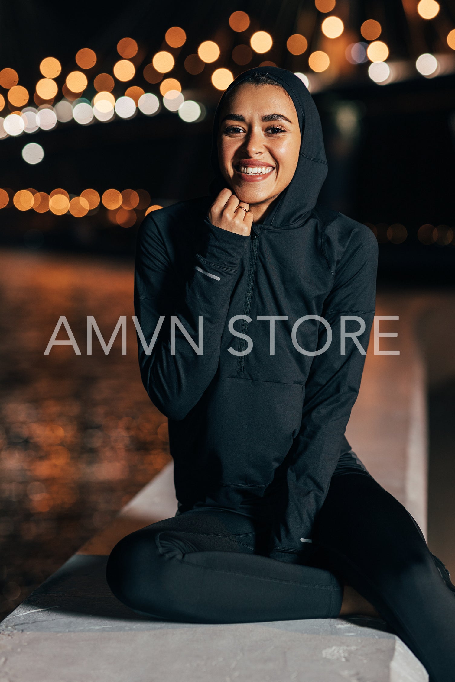 Beautiful middle east woman in hooded shirt sitting outdoors at night relaxing during a workout