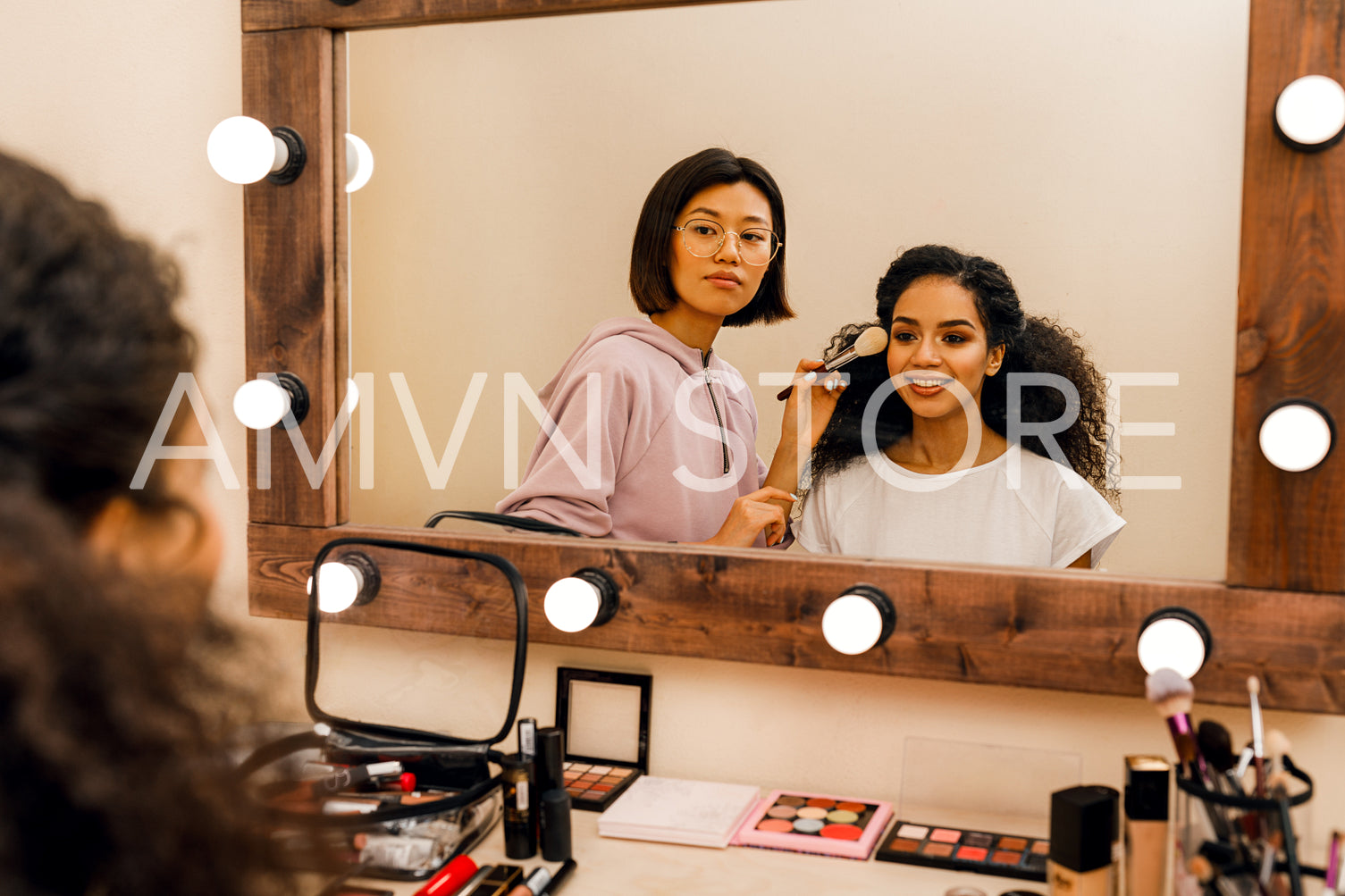 Two people in dressing room looking at mirror	
