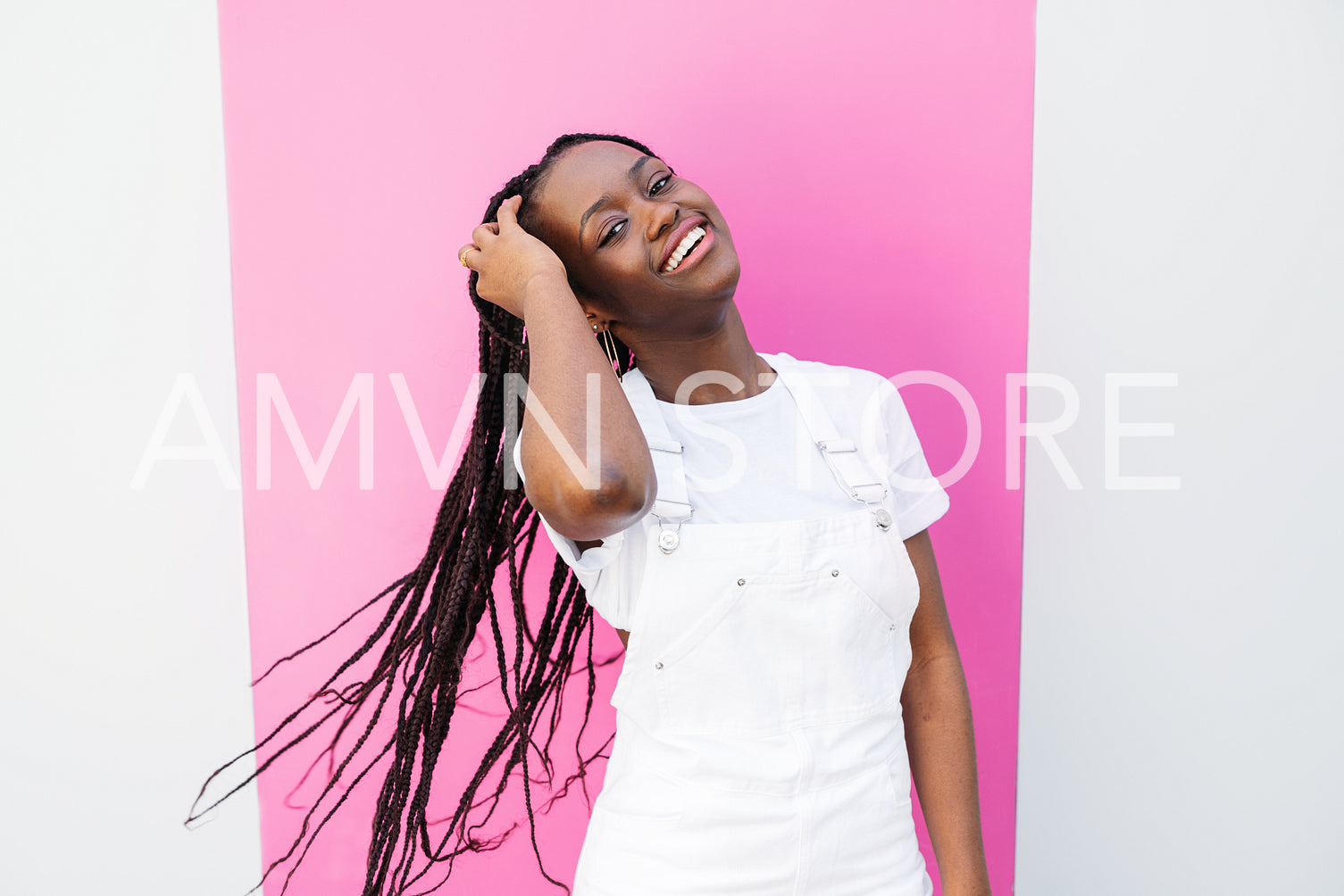 Positive girl in white casual clothes adjusting her braids 