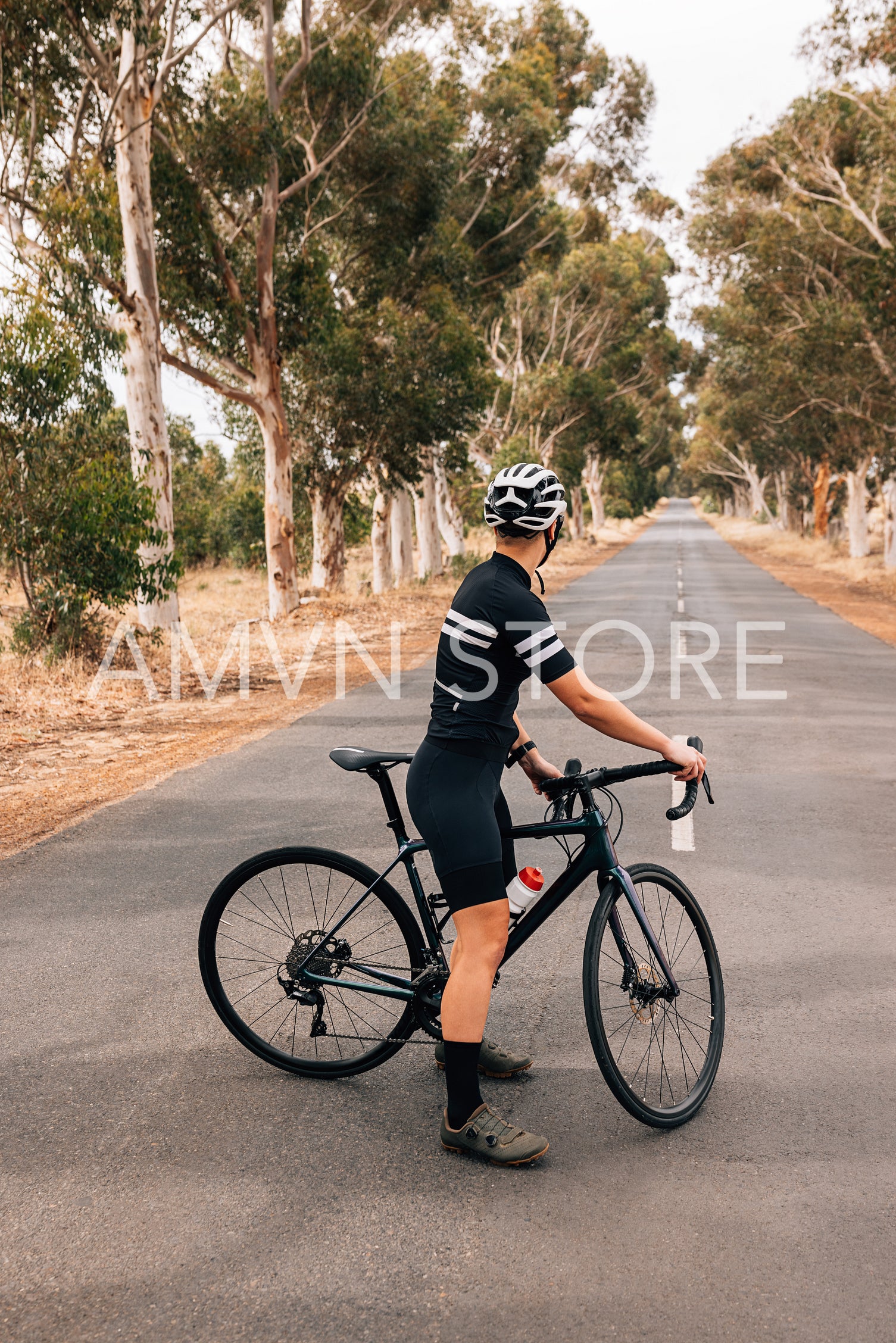 Back view of a professional woman cyclist standing on empty coun