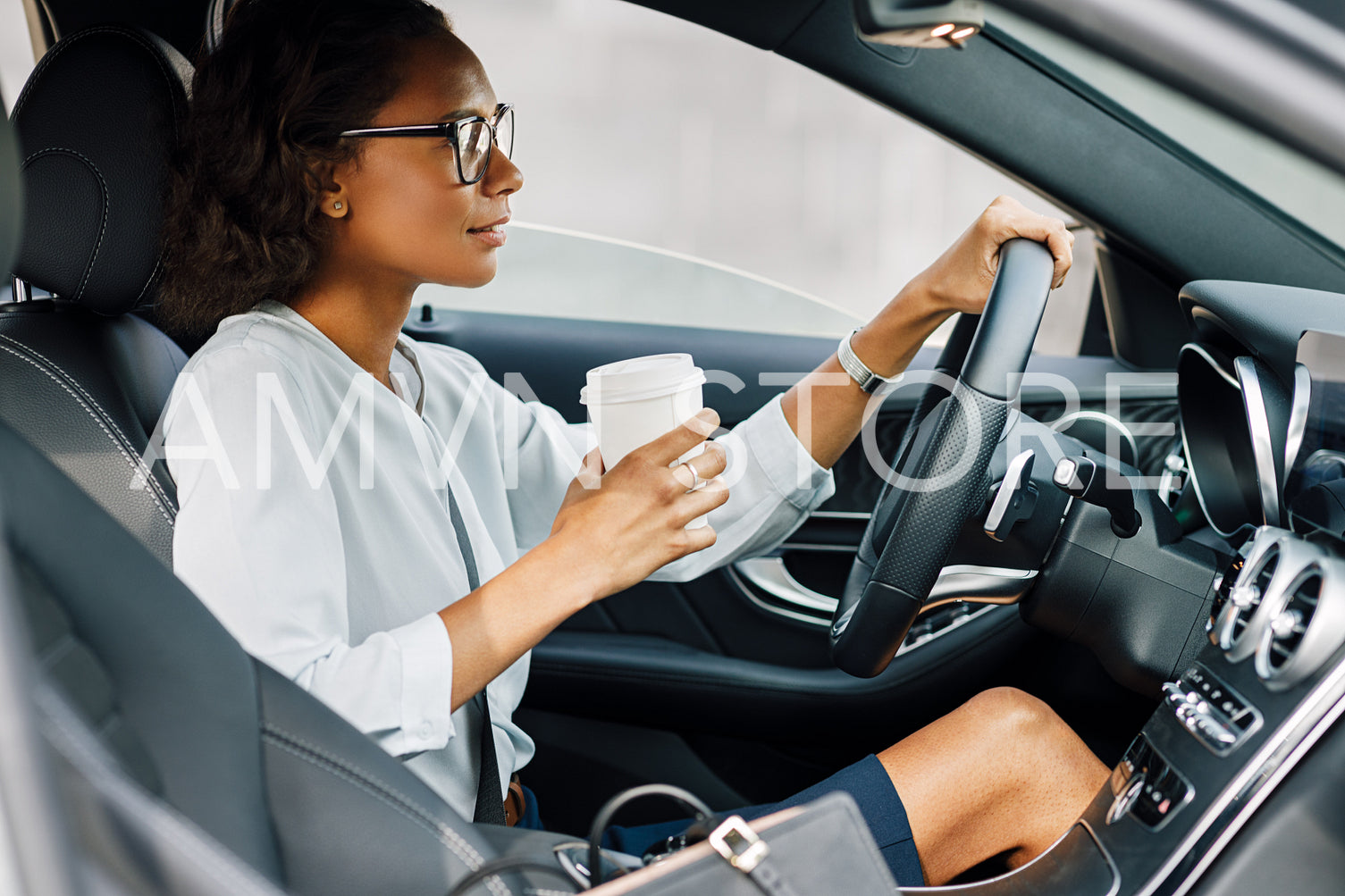 Businesswoman sitting in car. Side view of female driver holding a coffee.	