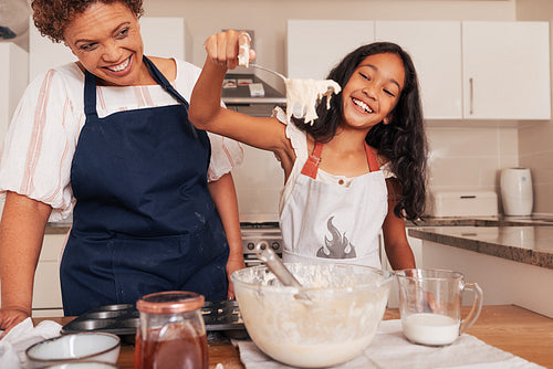 Happy girl scoops batter from a bowl with a spoon