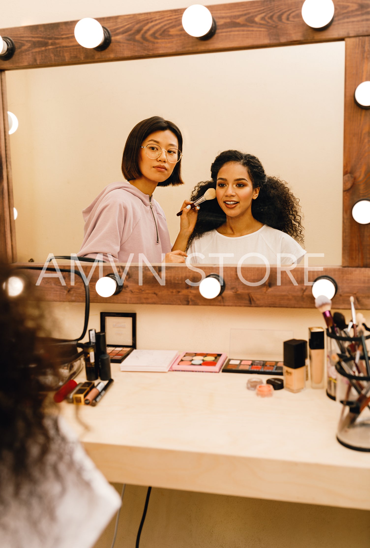 Model and makeup artist looking at a mirror preparing for a photo shoot	