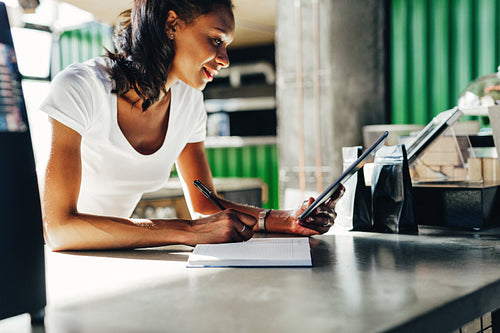 Woman reviewing business files on digital tablet at the counter in coffee shop