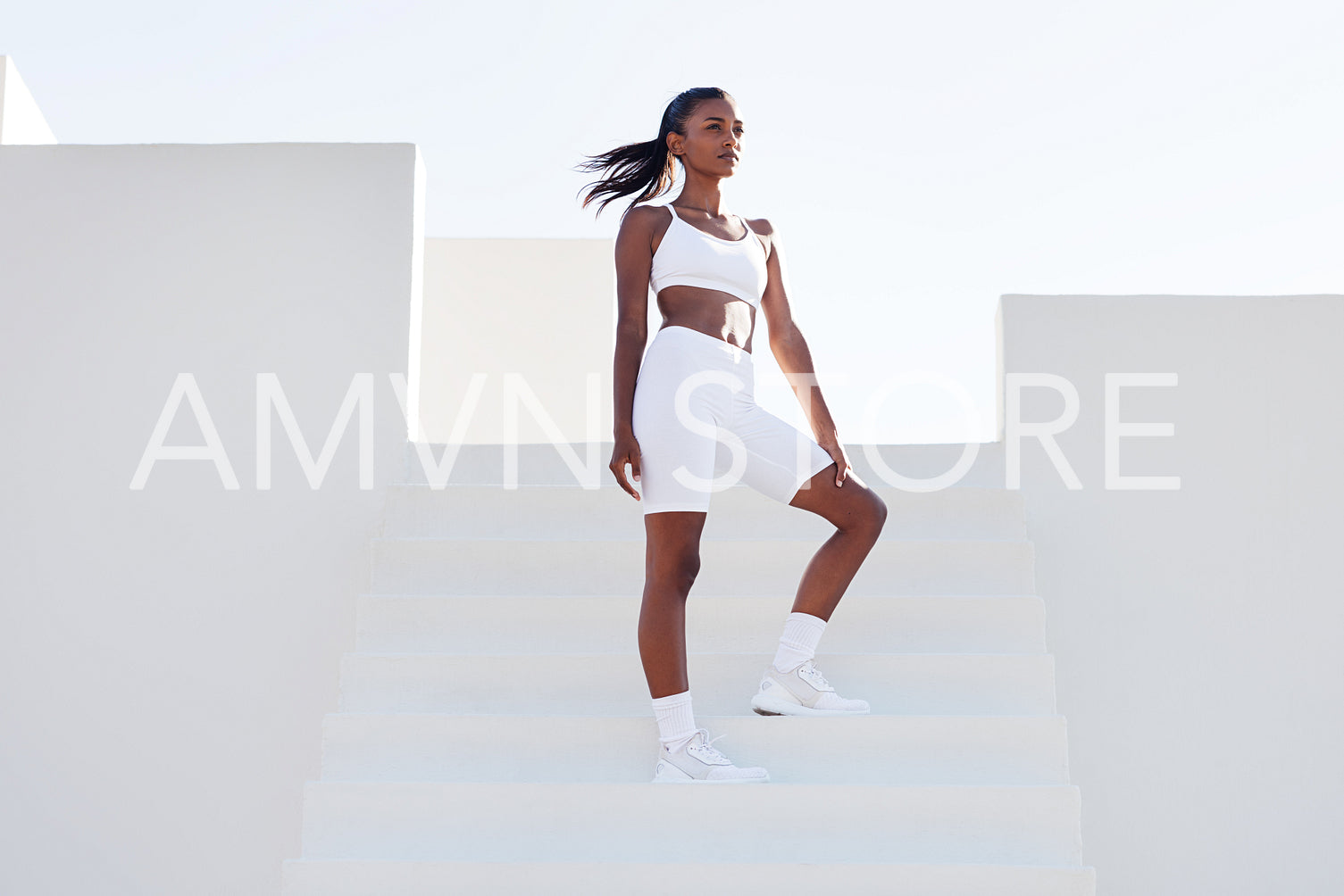 Full length of a slim woman relaxing during training. Young slim female on stairs looking away during exercises.