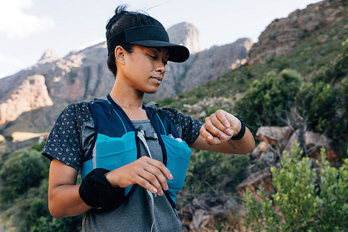 Woman hiker looking at smart watch. Female in sportswear checking a distance on fitness tracker.