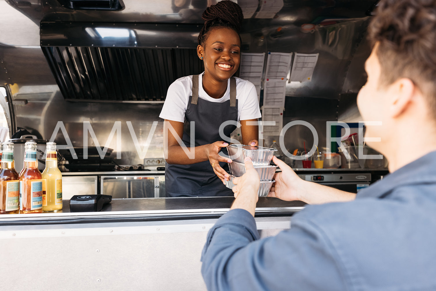 Young woman in apron working at food truck. Small business owner giving takeaway packaged food to customer.