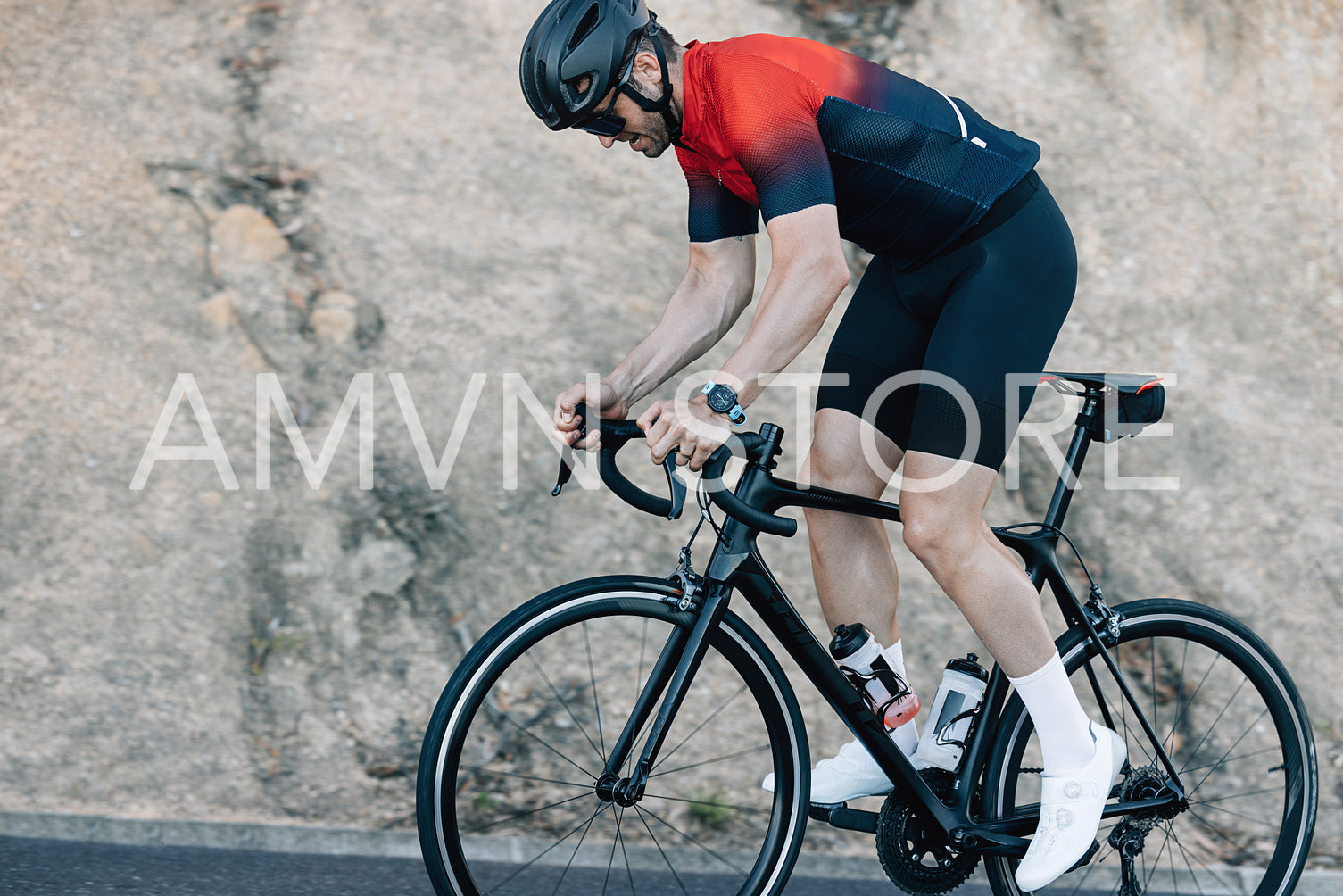 Male cyclist standing in the saddle while exercising on a road bike on a mountain road