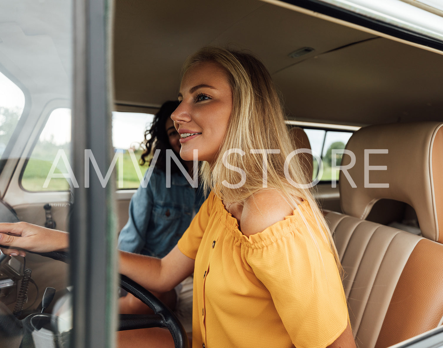 Blond woman driving a car. Two female friends sitting in a van during summer vacation.