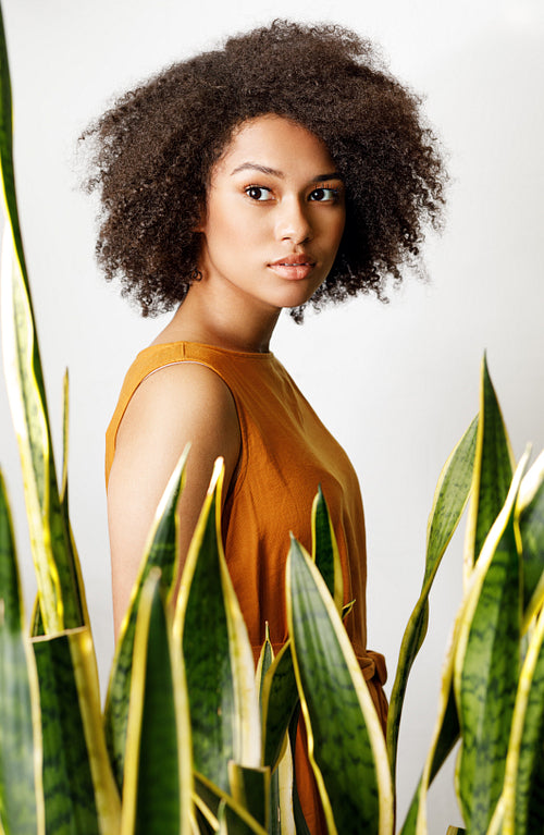 Portrait of a woman standing behind of a sansevieria plant