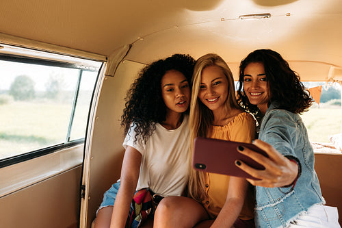 Group of female friends on a road trip taking selfie in a camper van